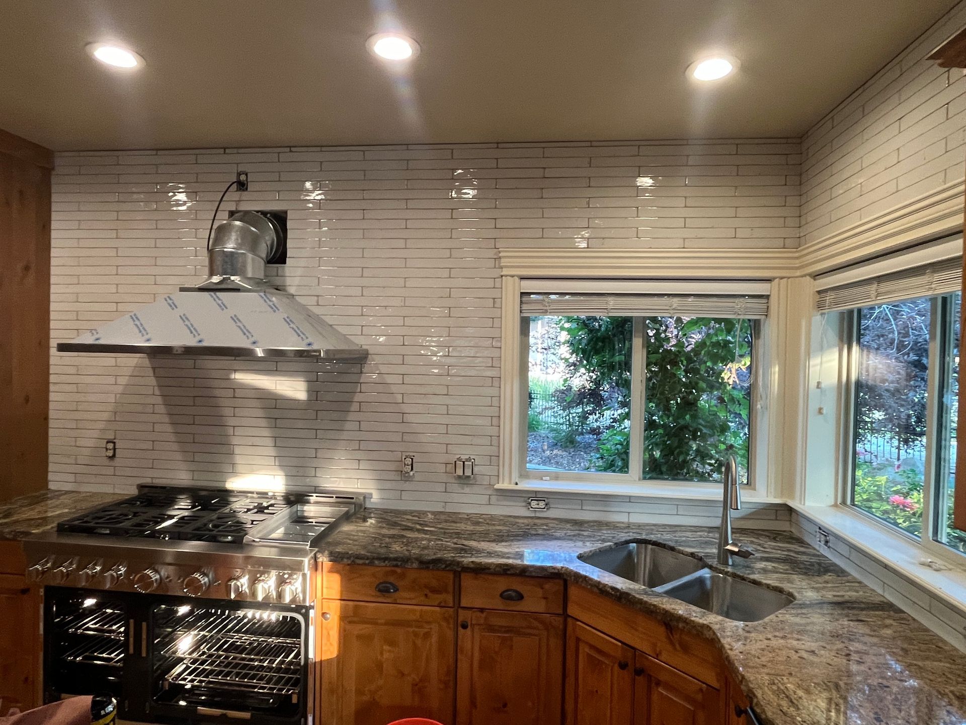 A kitchen with a stove , sink , and window.