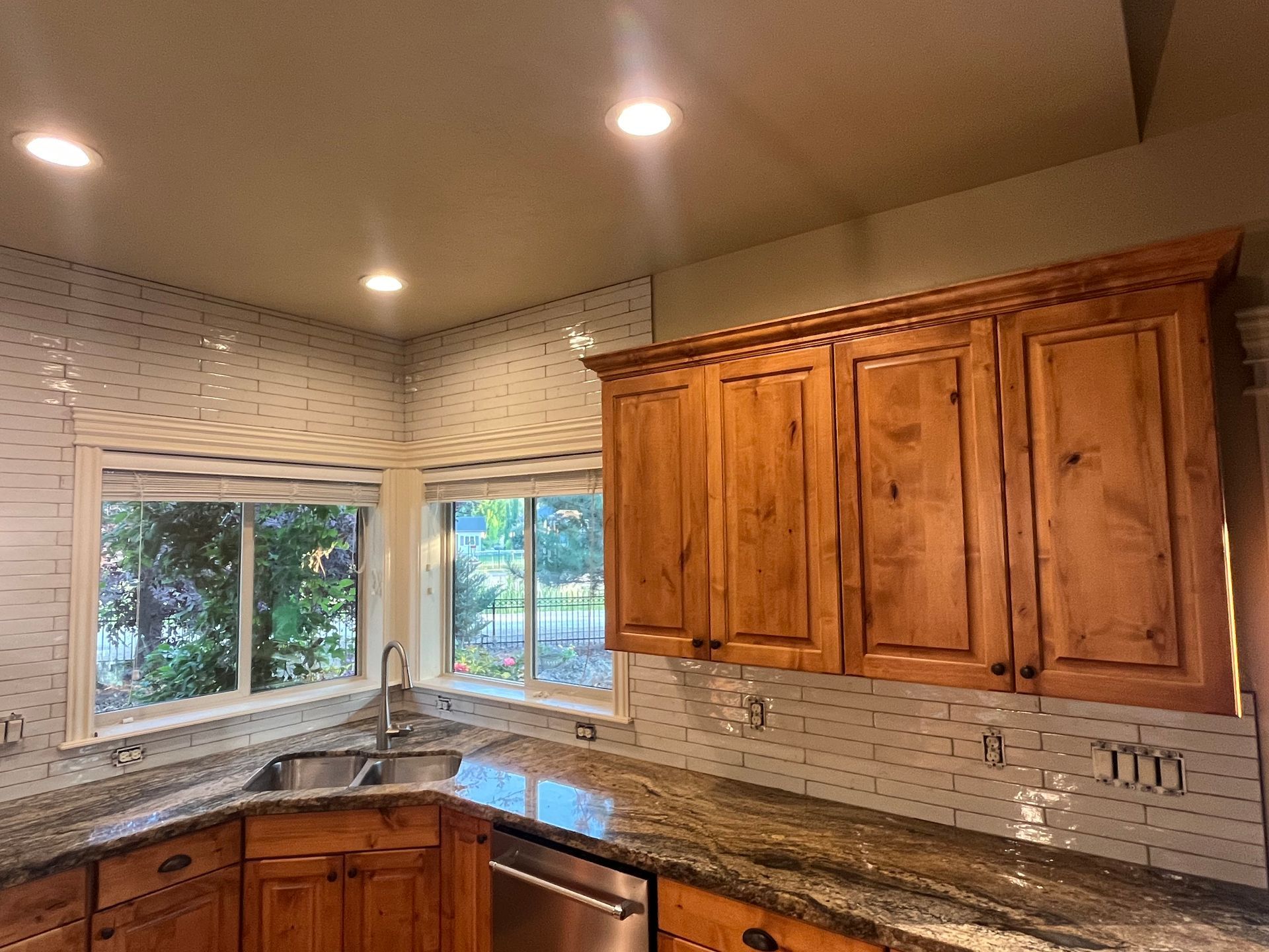 A kitchen with wooden cabinets , granite counter tops , a sink , and a window.