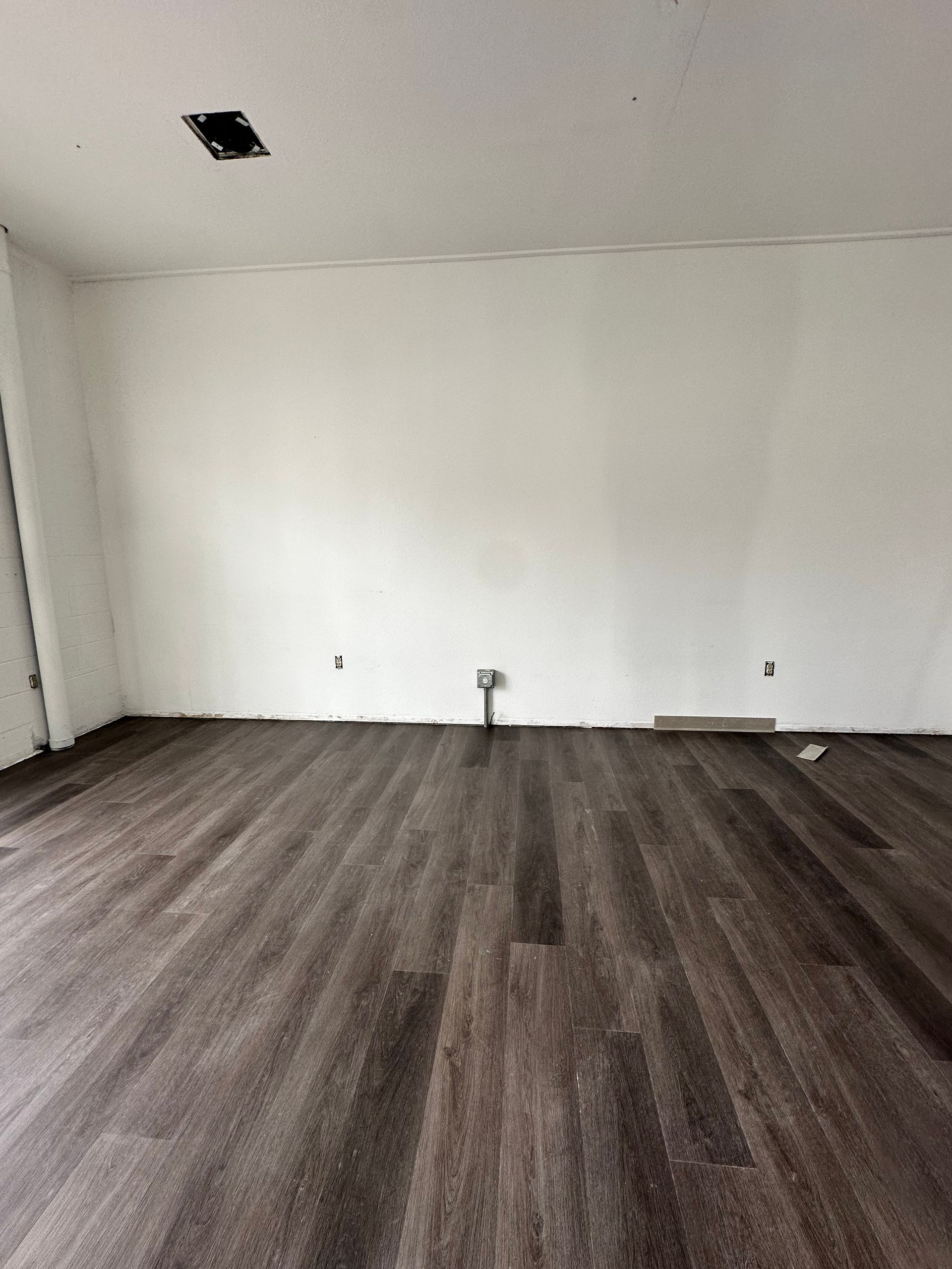 An empty room with a wooden floor and white walls.