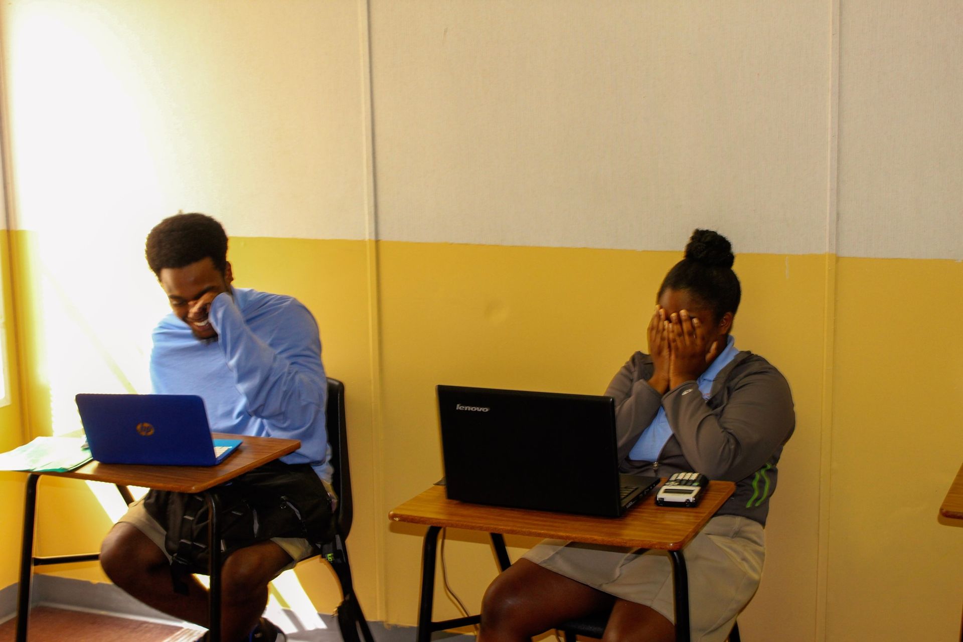 A man and a woman are sitting at desks with laptops