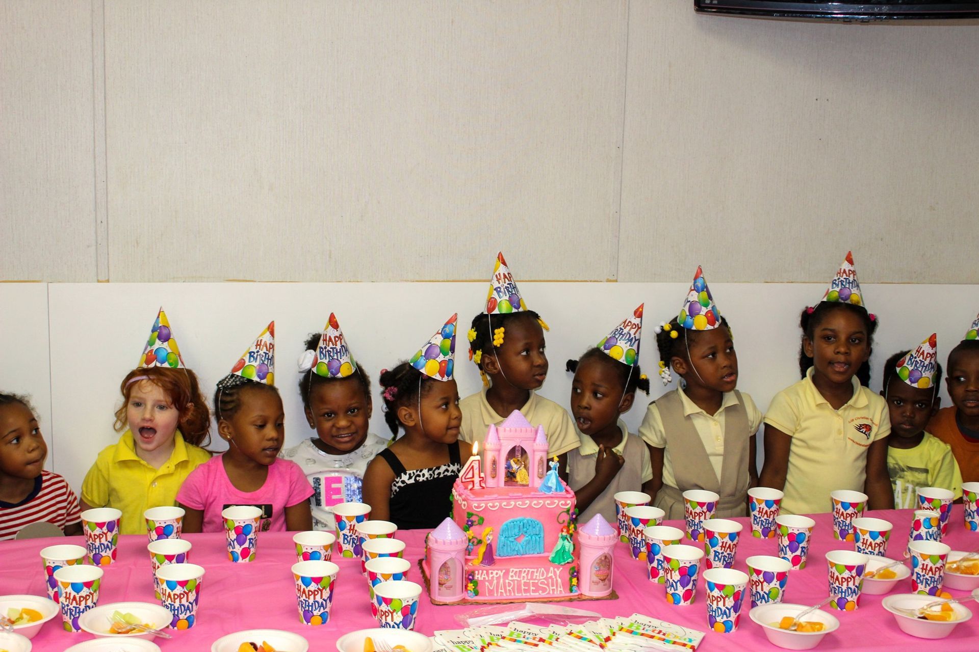 A group of children are sitting at a table with a birthday cake