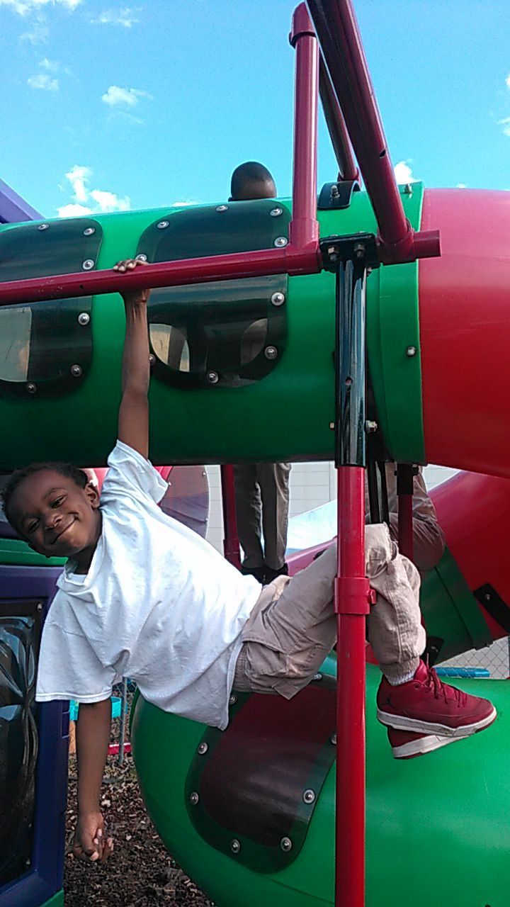 A young boy is hanging upside down on a playground structure