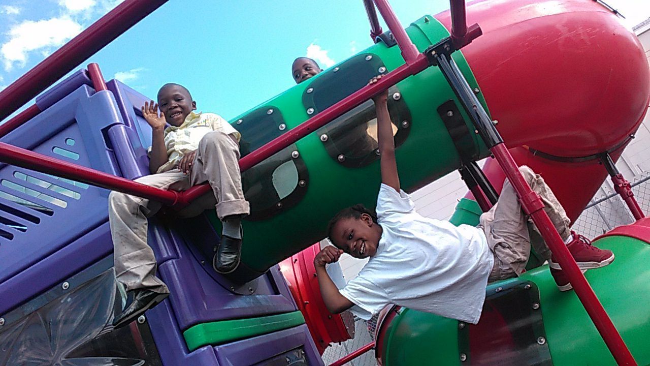 Two children are playing on a slide at a playground
