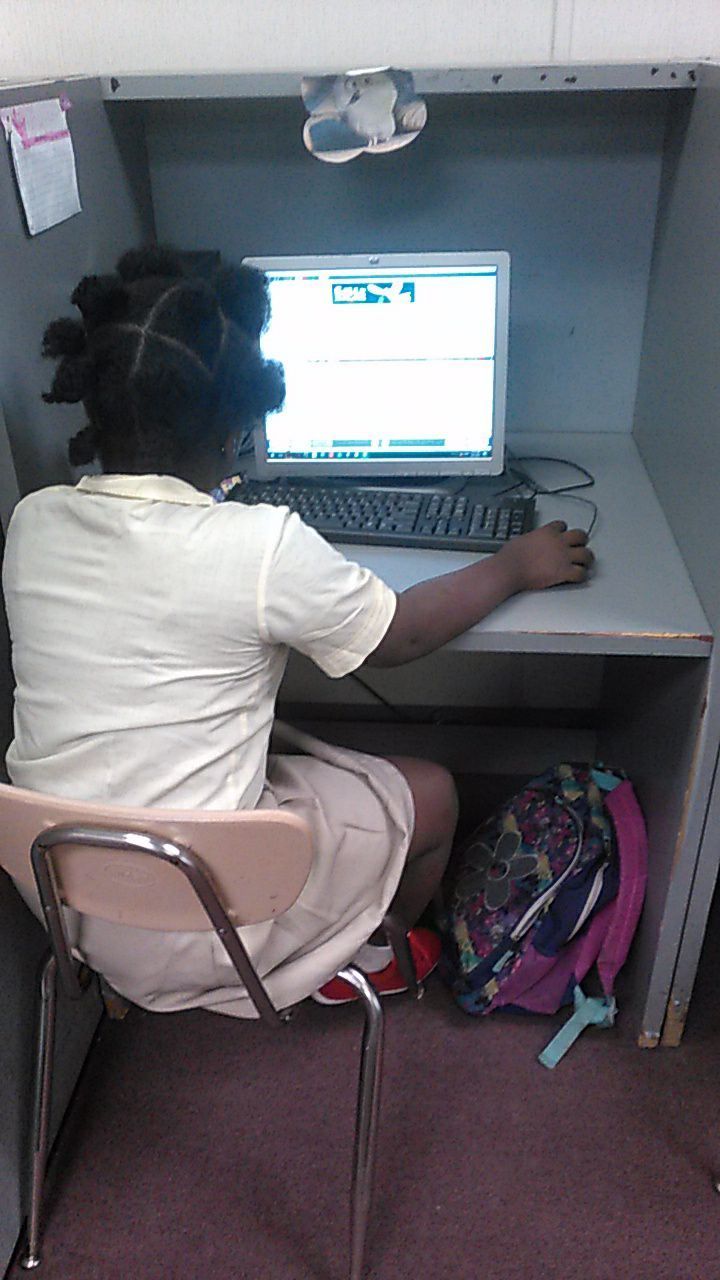 A girl is sitting at a desk using a laptop computer