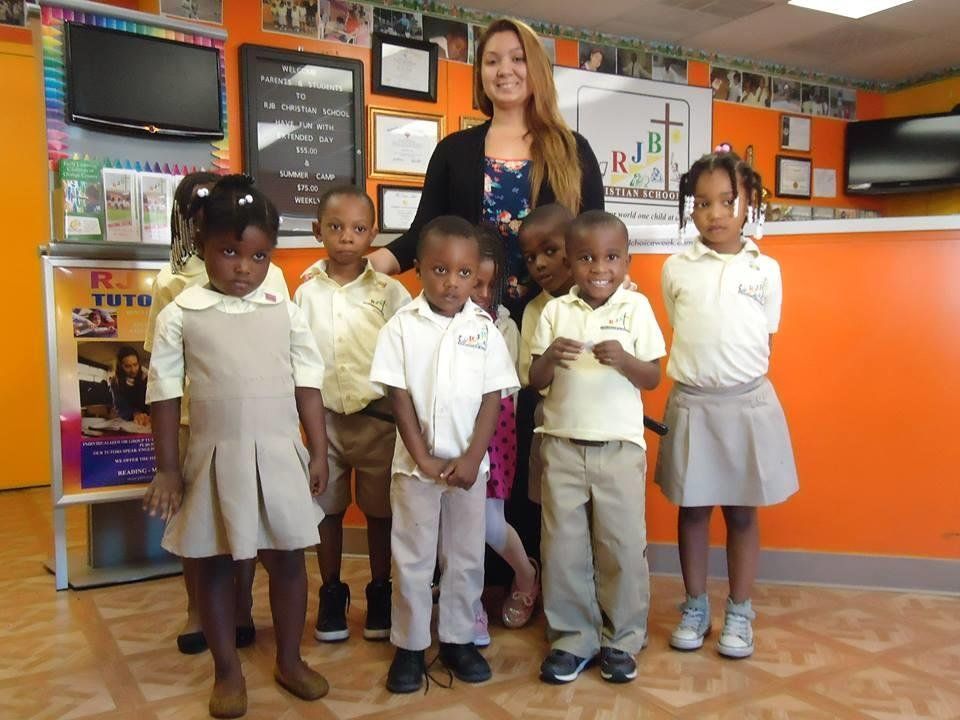 A group of children standing in front of a sign that says tutu