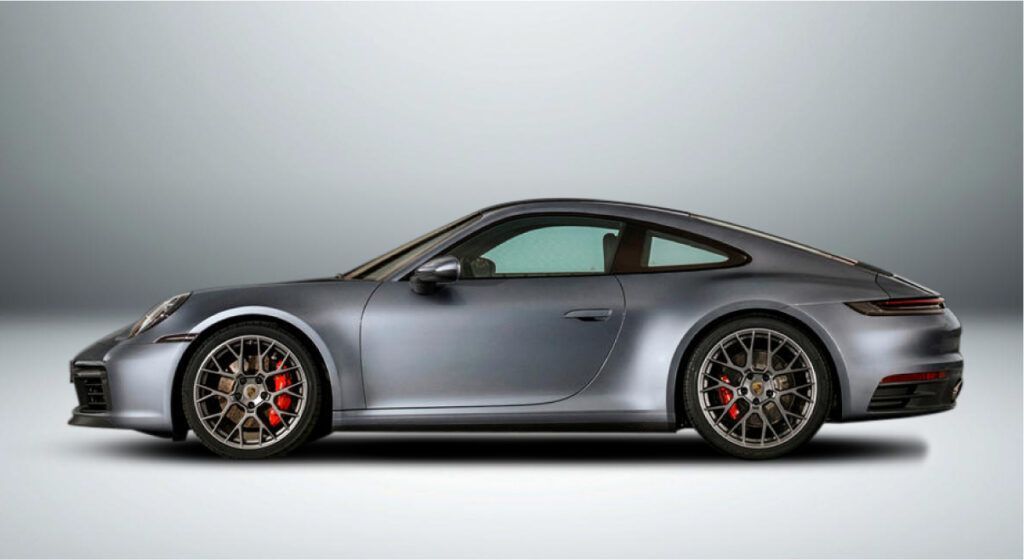 Um porsche 911 prateado está sobre uma superfície branca.