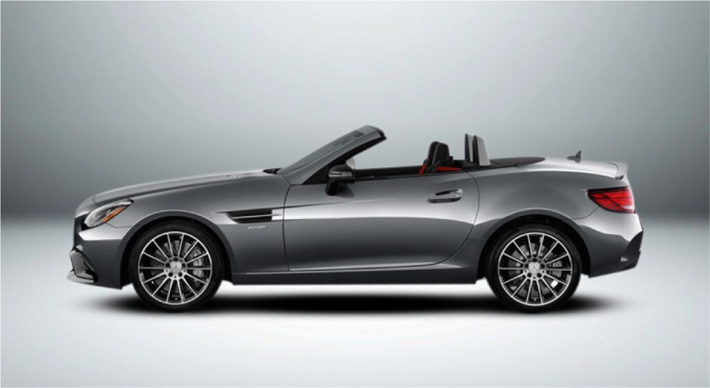 Um carro esportivo conversível prateado com a capota voltada para baixo sobre um fundo branco.