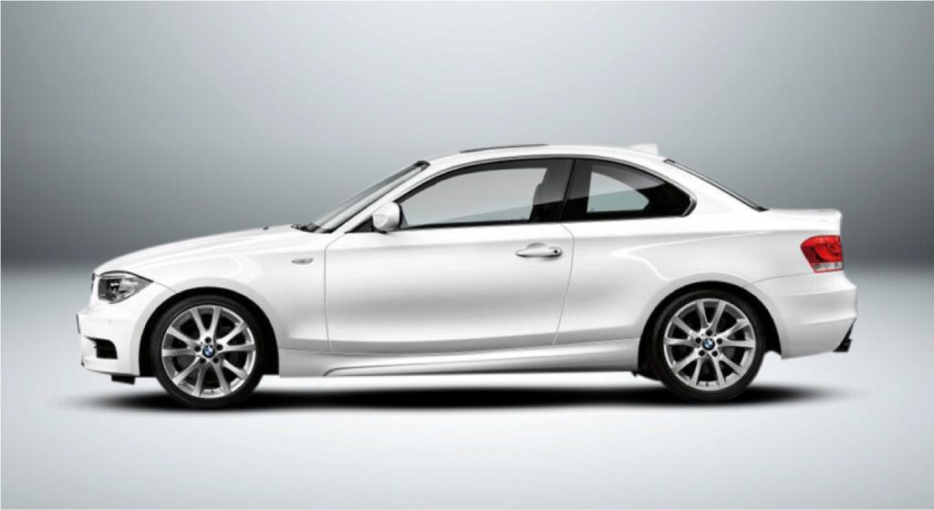 Um cupê bmw série 1 branco está sentado em uma superfície branca.