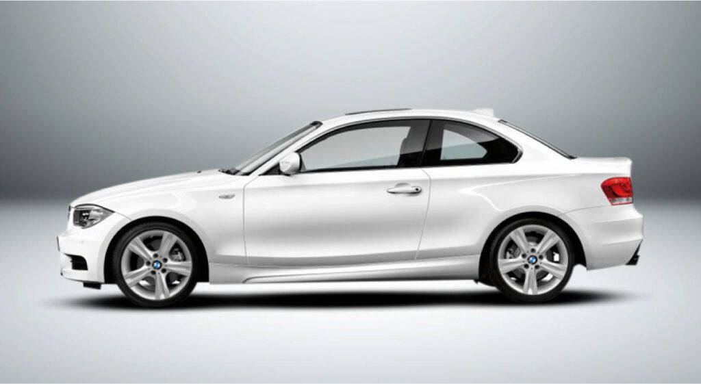 Um cupê bmw série 1 branco está sentado em uma superfície branca.