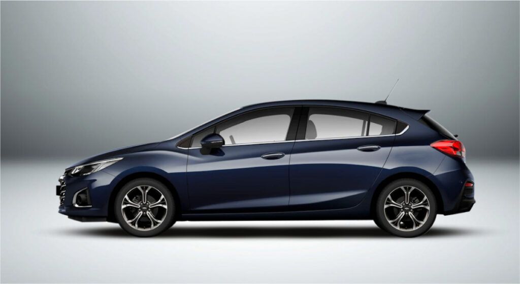 Um carro hatchback azul está sentado em uma superfície branca.