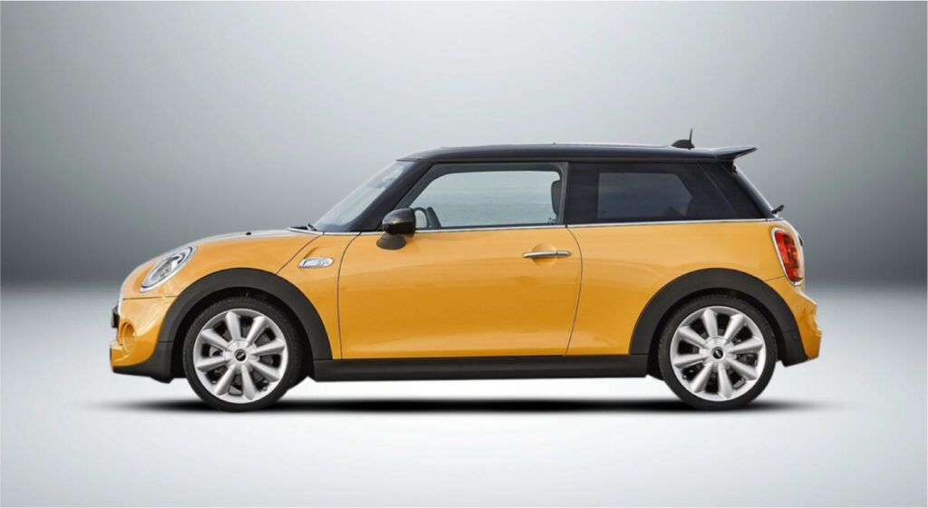 Um mini cooper amarelo está sentado em uma superfície branca.