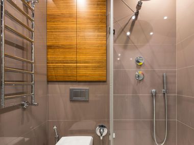Modern bathroom with glass shower, chrome towel rack, and wood panel accent wall
