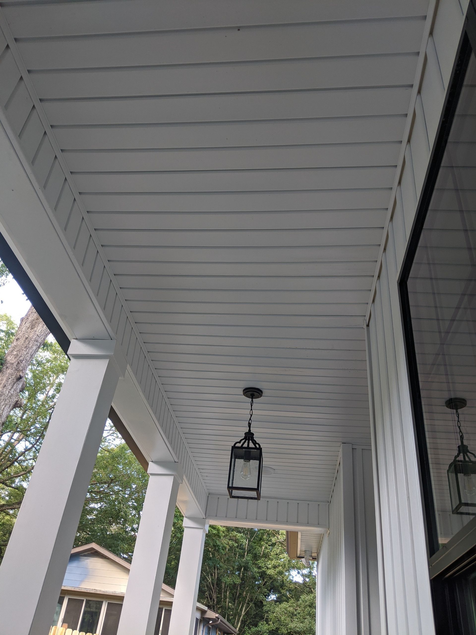 White porch ceiling with a hanging lantern, supported by white columns.