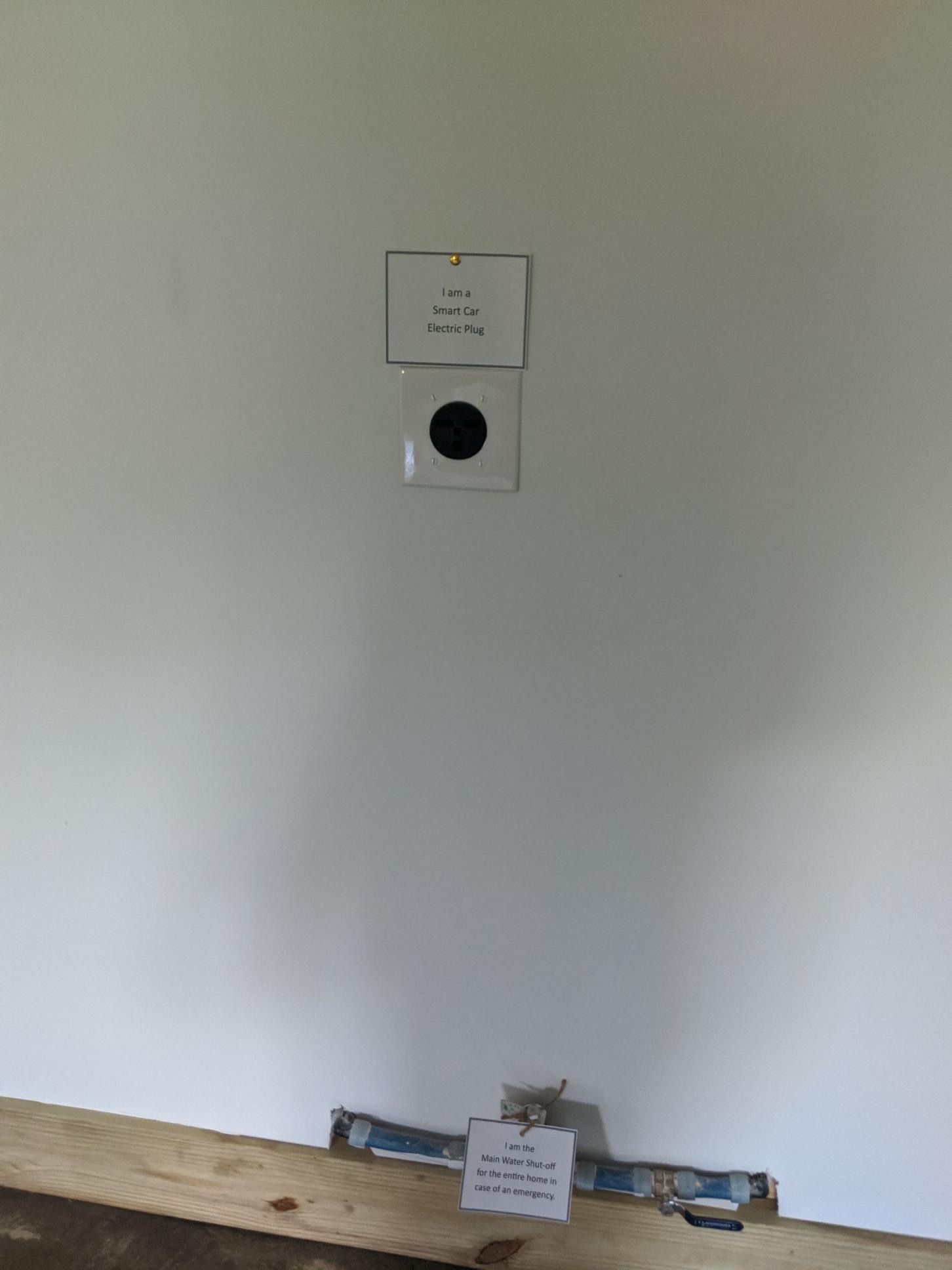 White wall with a black circle and two labels, one at the bottom, with a wooden plank below.