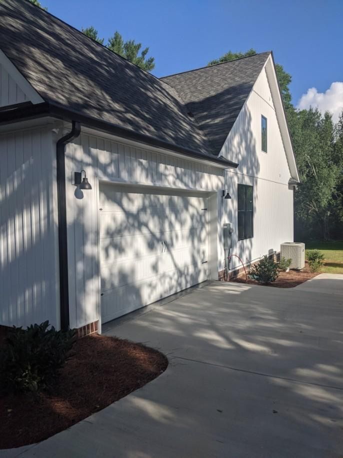 White house with attached garage; white siding, black trim, asphalt roof, concrete driveway.