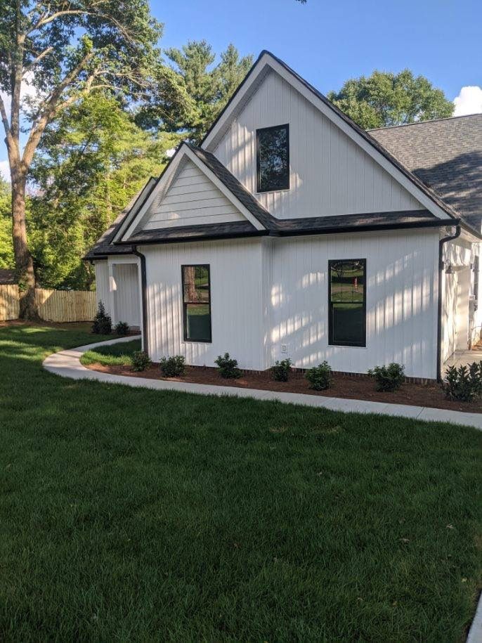 White house with black trim, two windows, and a small garden.