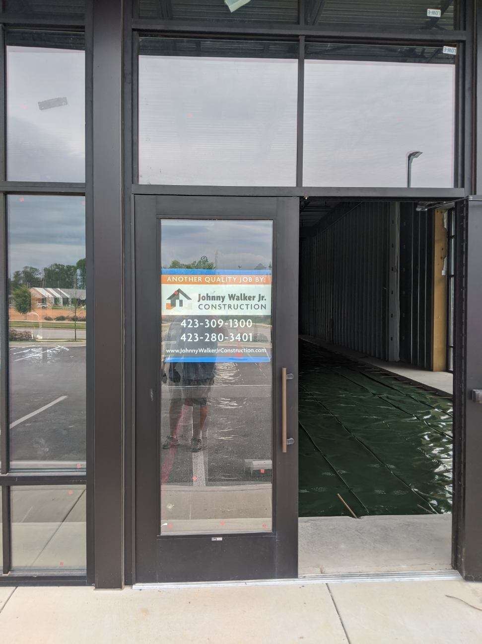 Storefront with glass door; open, revealing an unfinished interior.