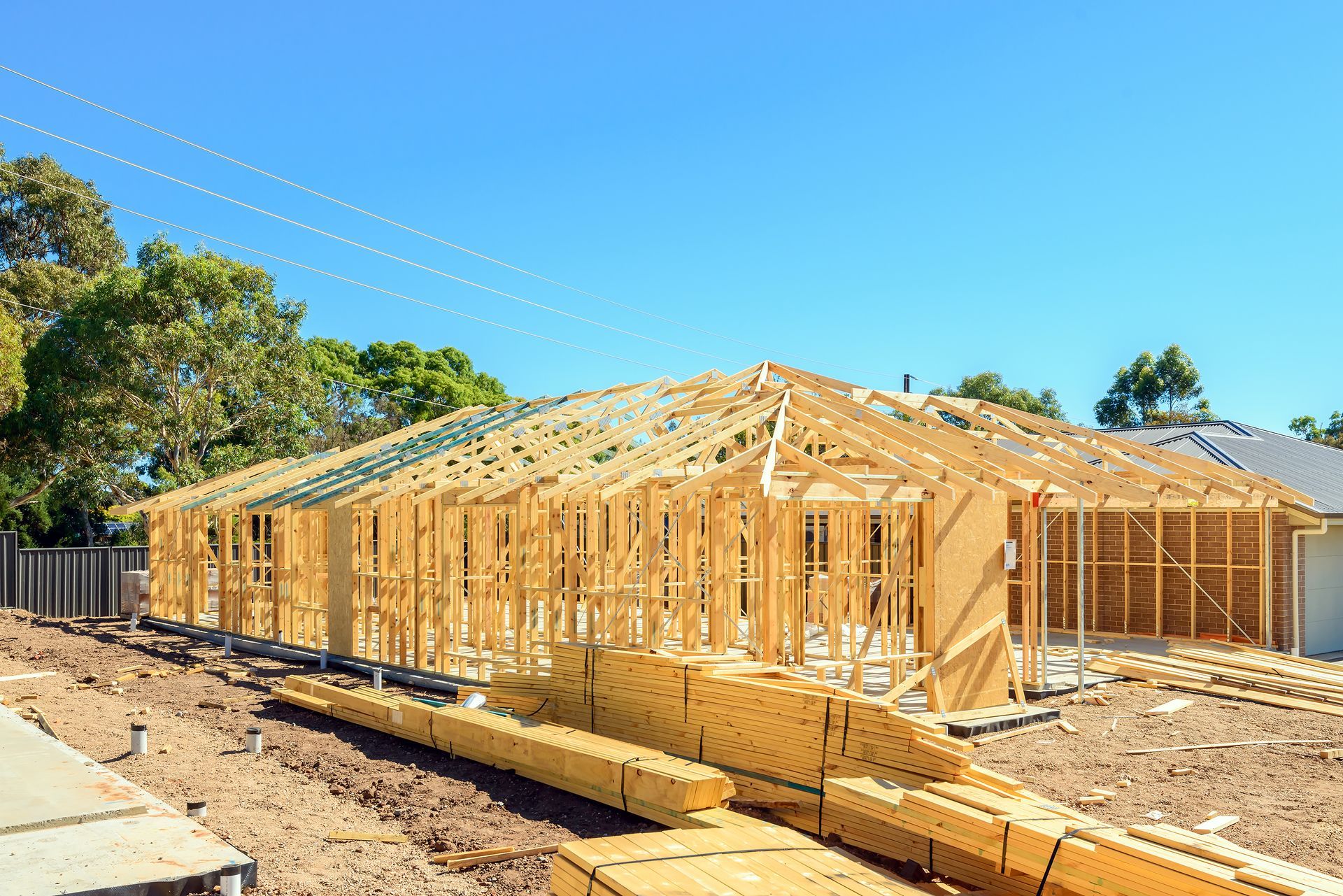 Wooden frame of a house under construction, set against a blue sky.
