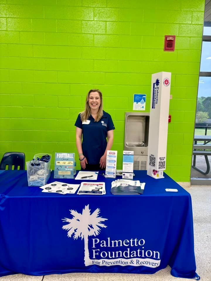 Woman at a table with Palmetto Foundation logo, green wall background.