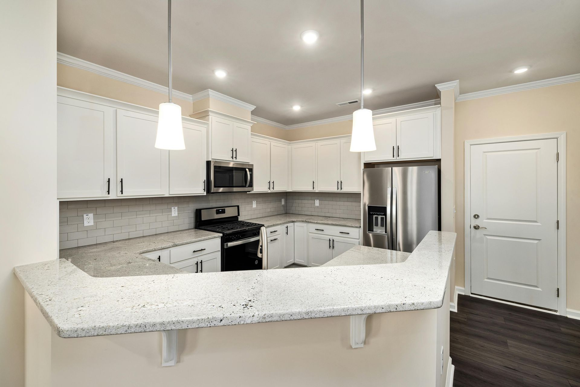 Bright modern kitchen with white cabinets, stainless appliances, and a speckled white island counter