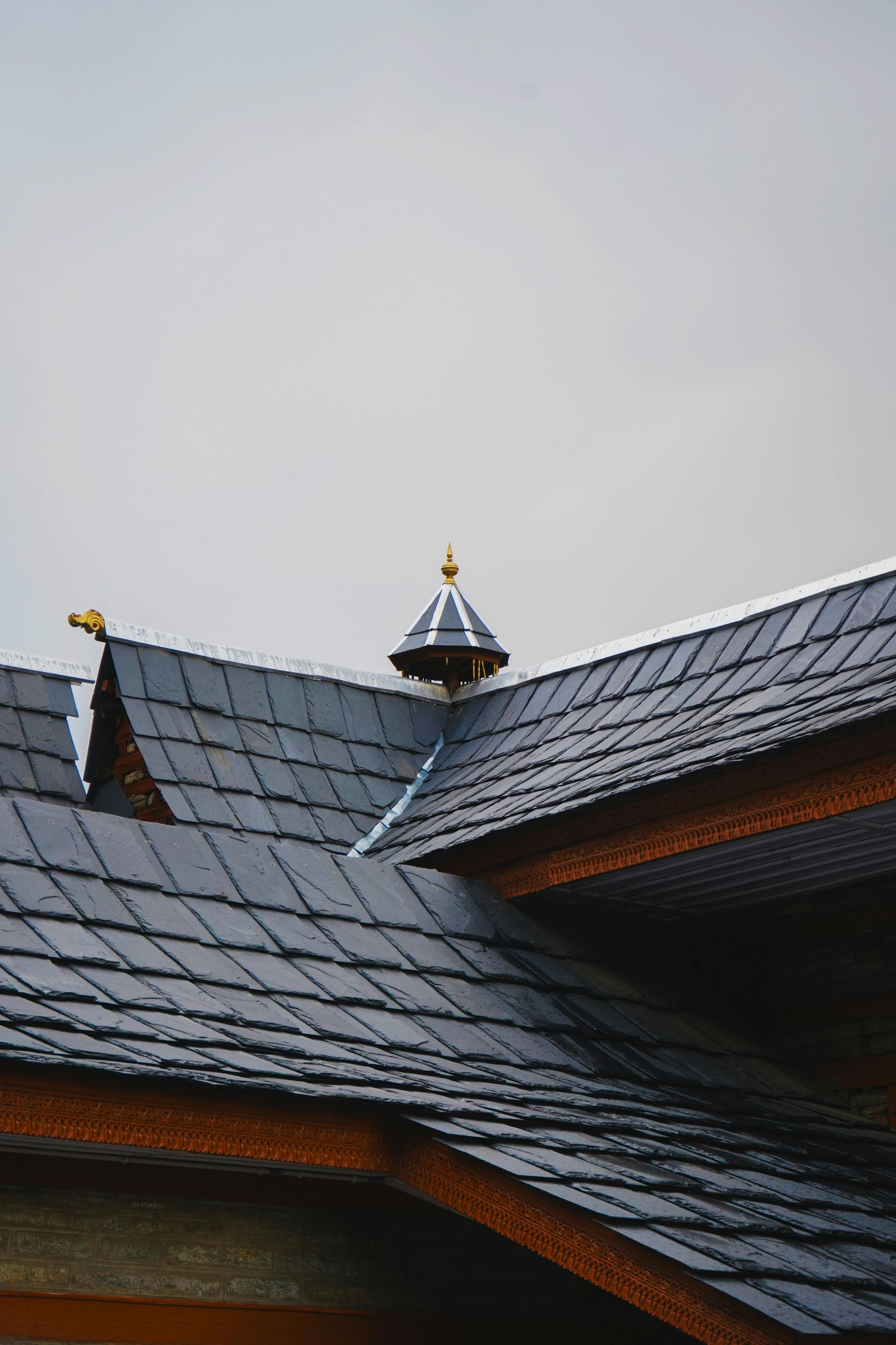 Slate roof with a small central turret against a gray sky