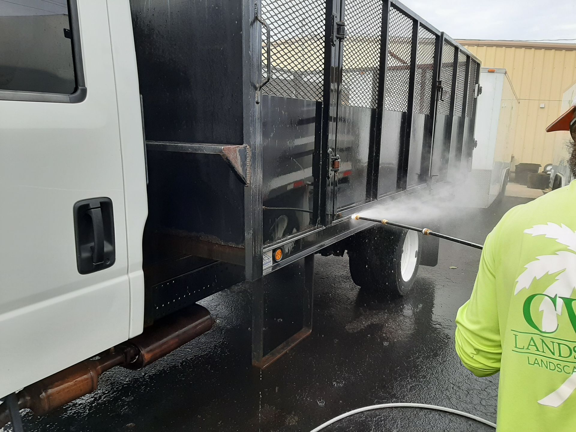 A man in a green shirt is washing a truck