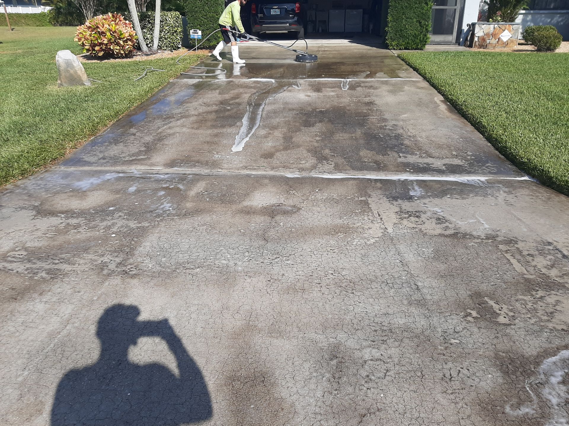 A man is cleaning a driveway with a broom.