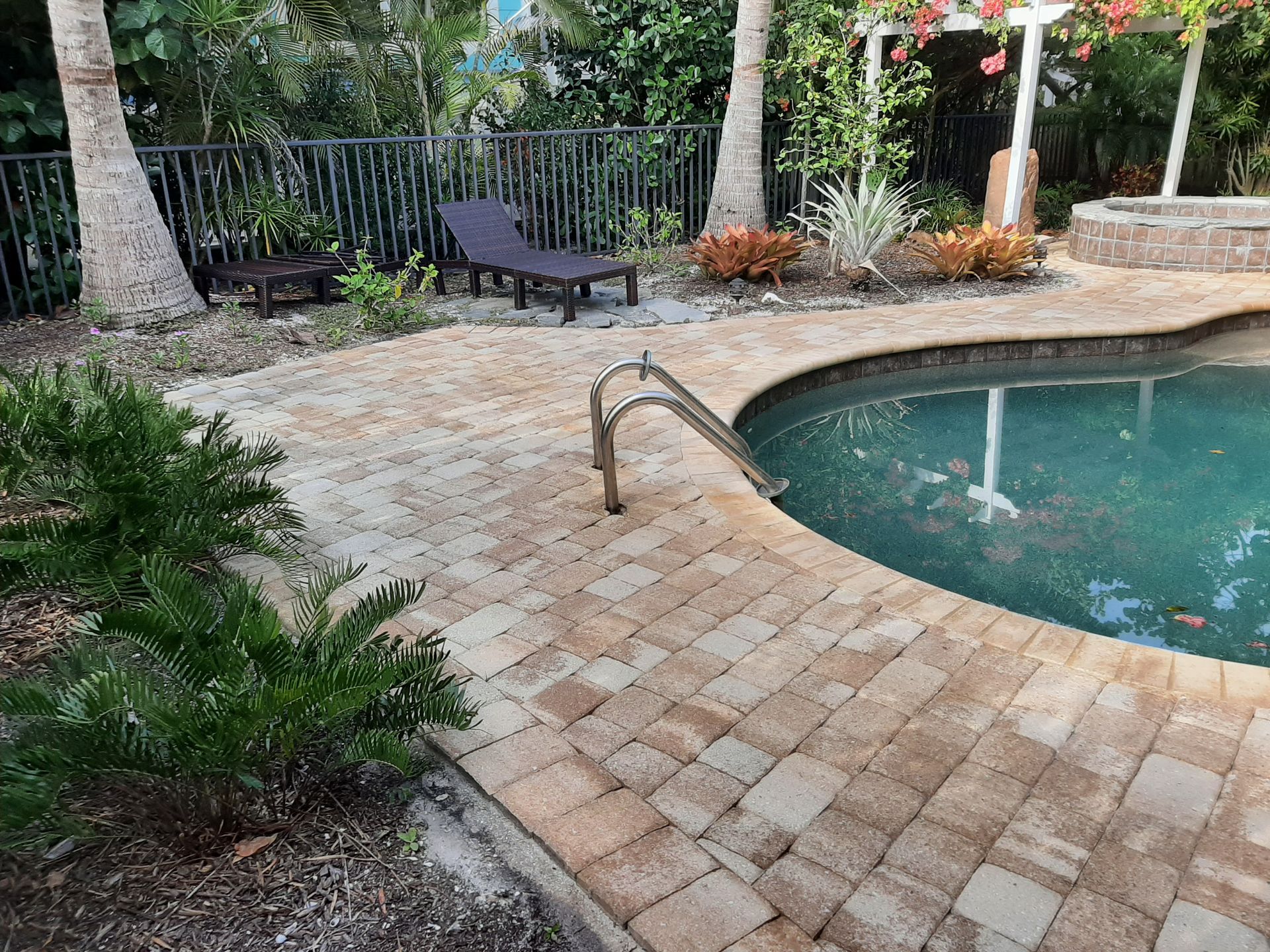 A large swimming pool with a brick walkway surrounding it.