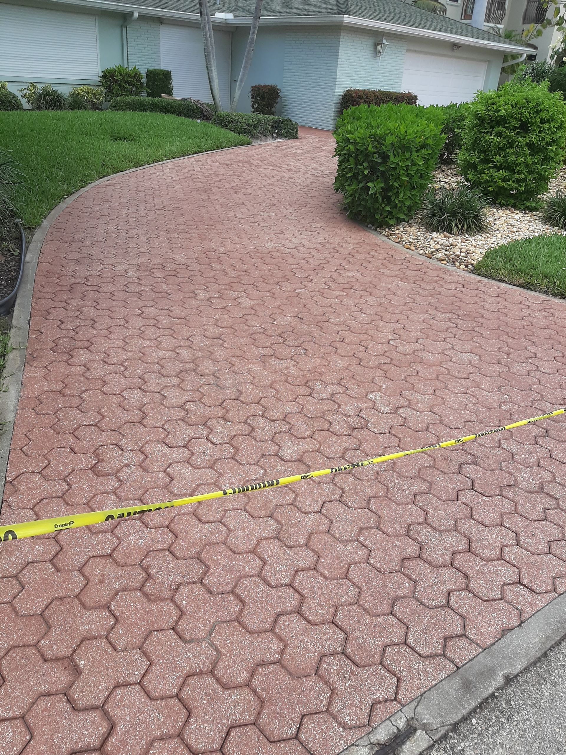 A brick walkway leading to a house with a yellow tape.
