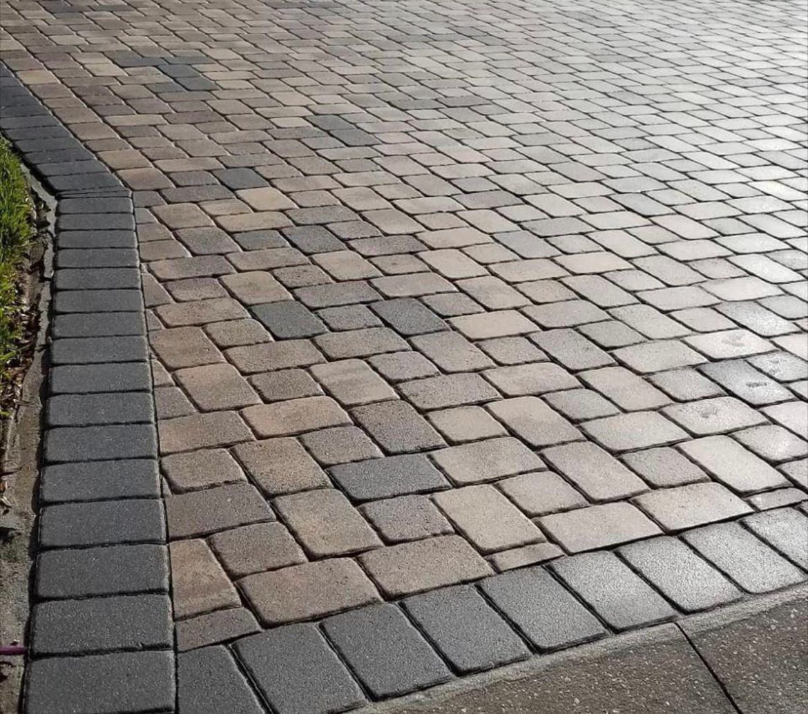 A close up of a brick driveway with a black border