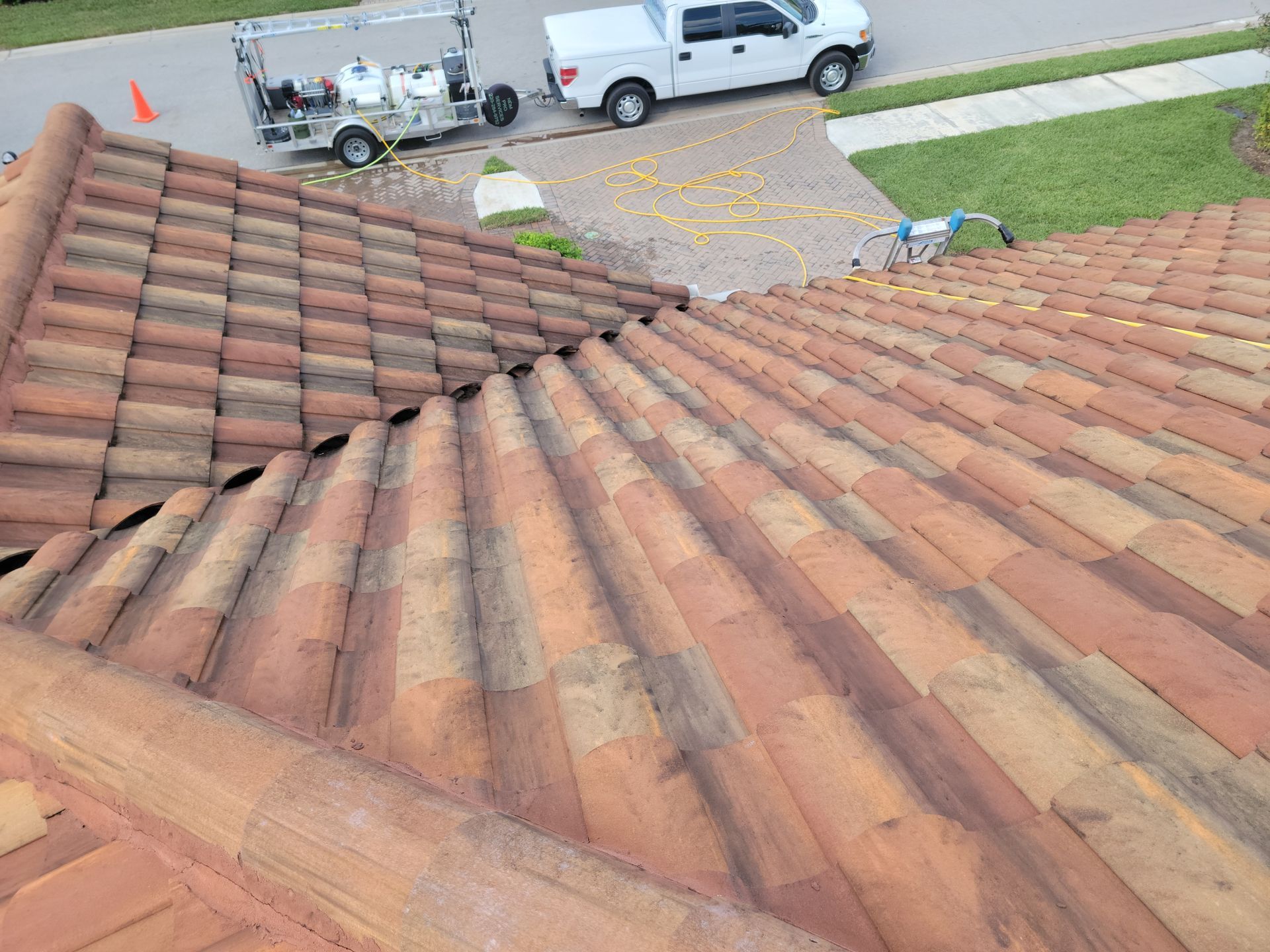 A white truck is parked on the side of the road next to a tiled roof.