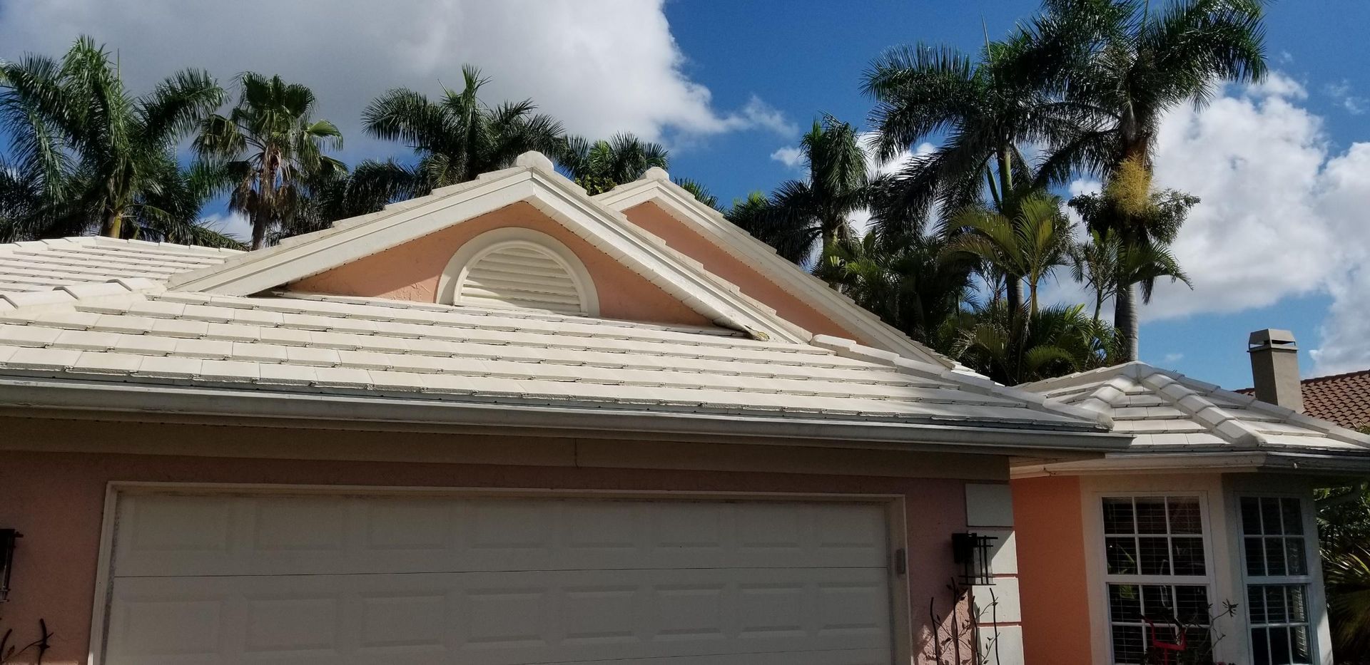 A pink house with a white garage door and a white roof.
