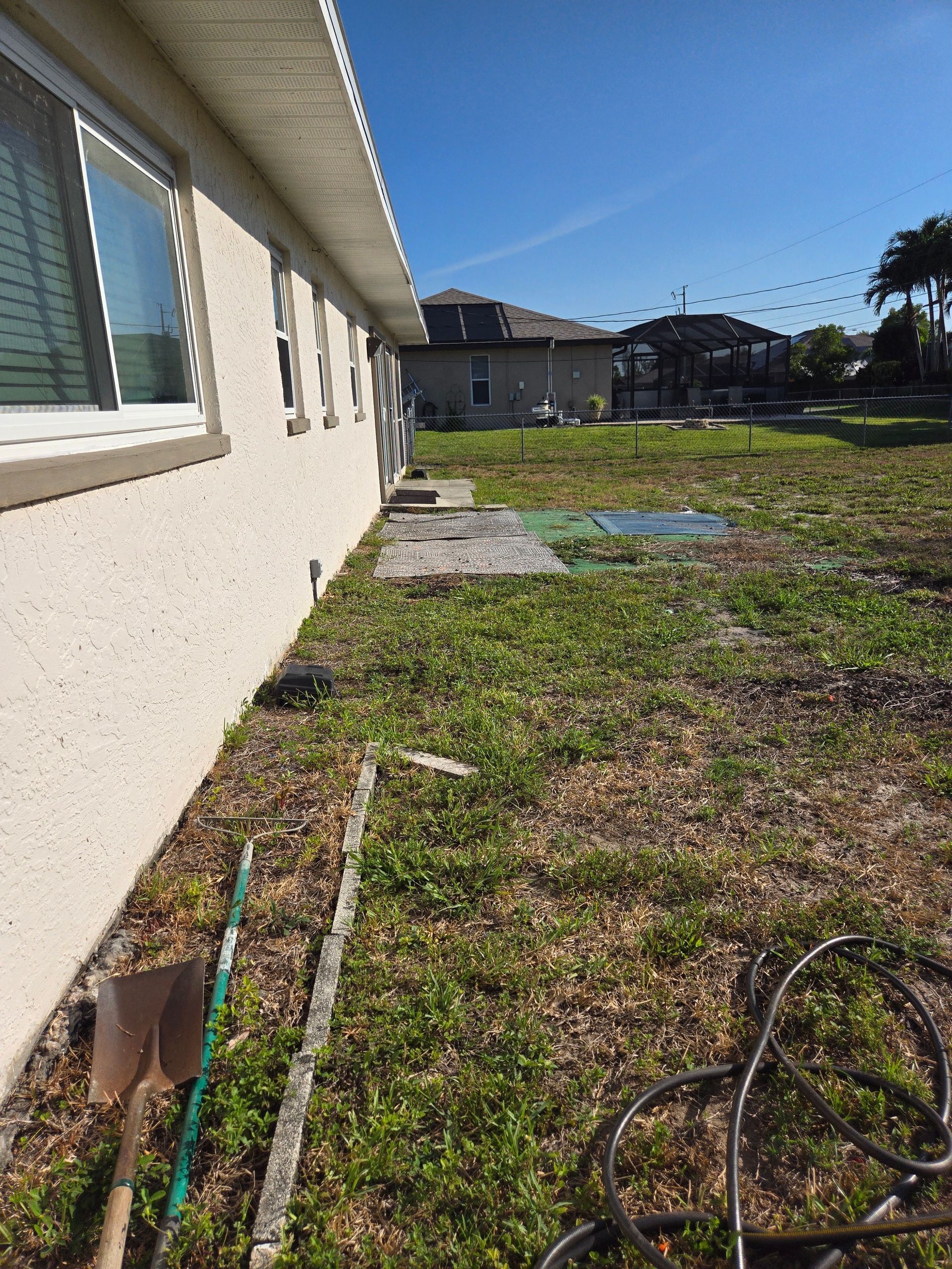 A house with a lot of grass and a shovel in front of it.