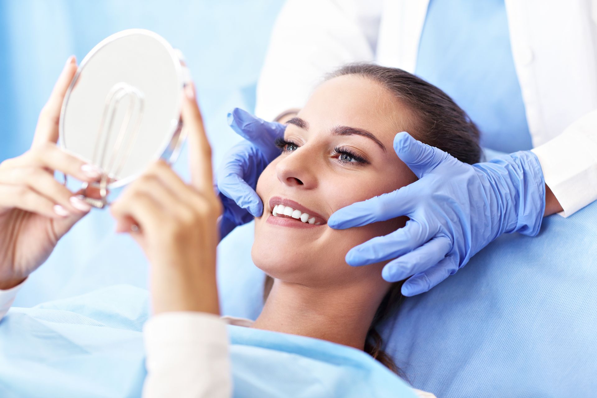 An adult woman is visiting the dentist's, looking at her smile after treatment.
