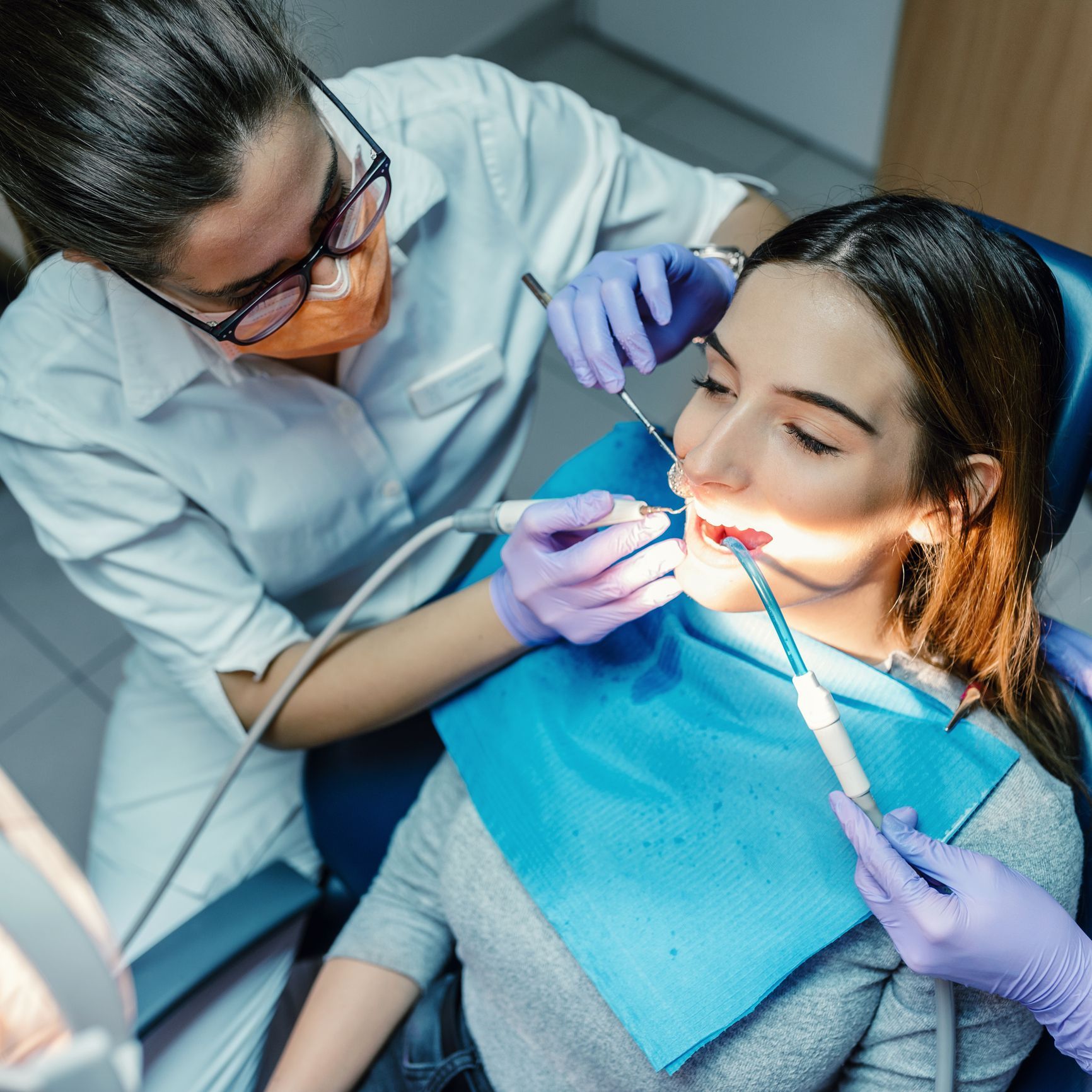 A female dentist is examining a young patient's teeth using dental tools in a clinic. A female dentist is examining a young patient's teeth using dental tools in a clinic.