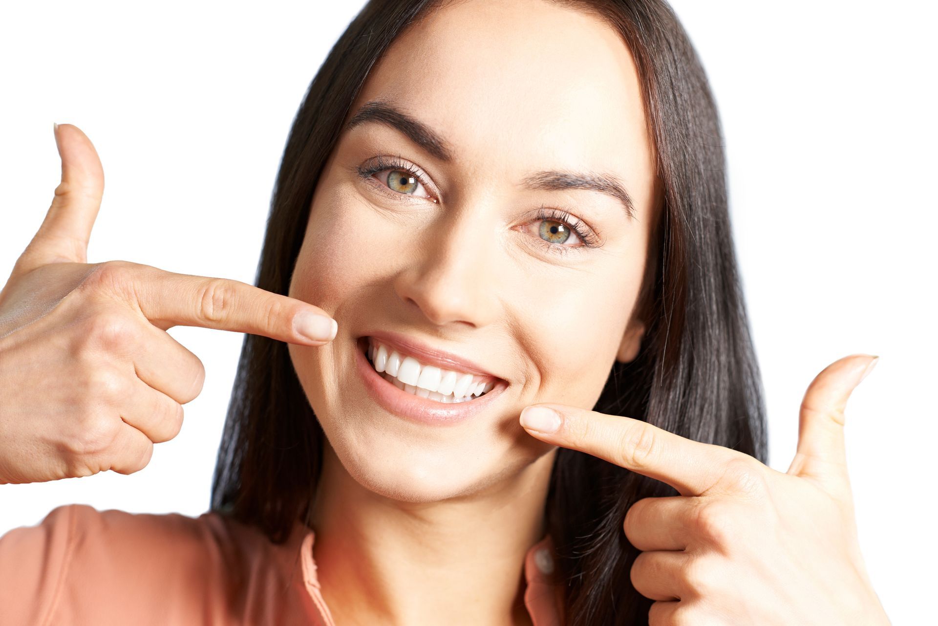 A woman is pointing at her teeth and smiling.