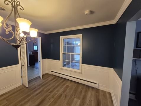 Dining room with dark blue walls, white wainscoting, a chandelier, and light wood flooring.