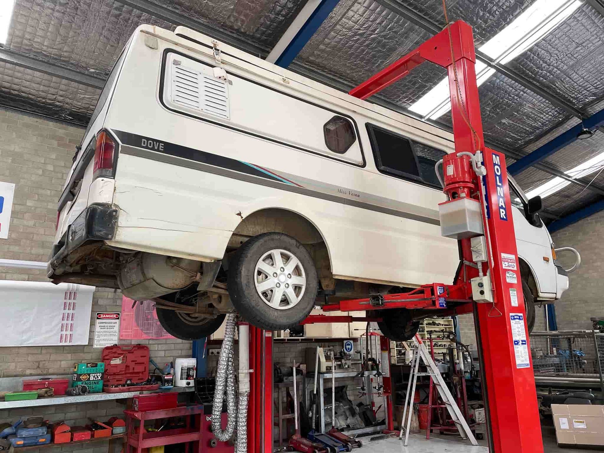 A White Van is Sitting on Top of a Red Lift in a Garage — Town & Country Removals In Taree, NSW