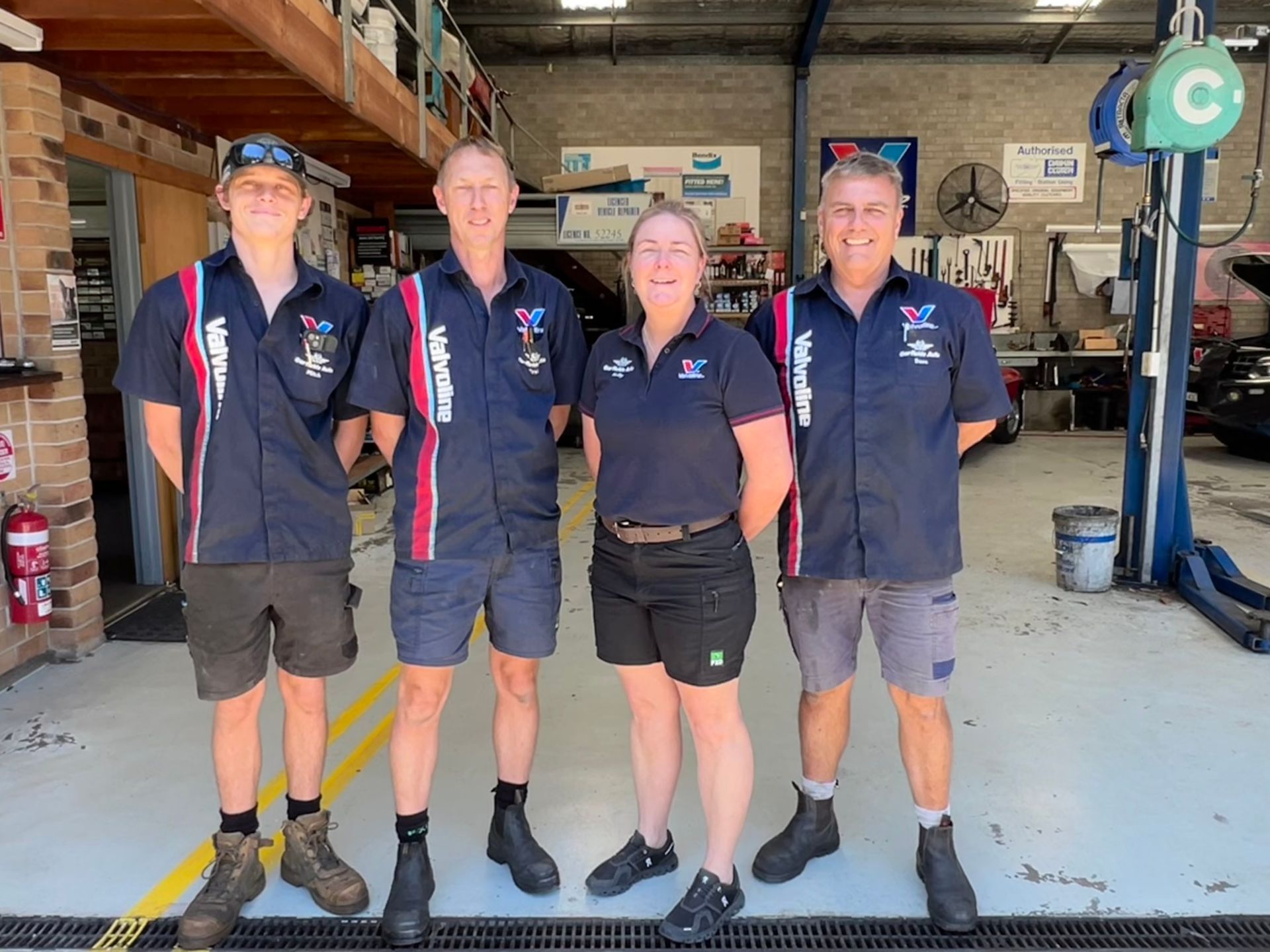 A Group of Men Are Standing in Front of a Car in a Garage — Town & Country Removals In Taree, NSW