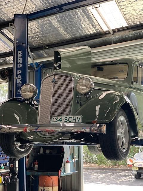 A Green Car is Sitting on a Lift in a Garage — Town & Country Removals In Taree, NSW
