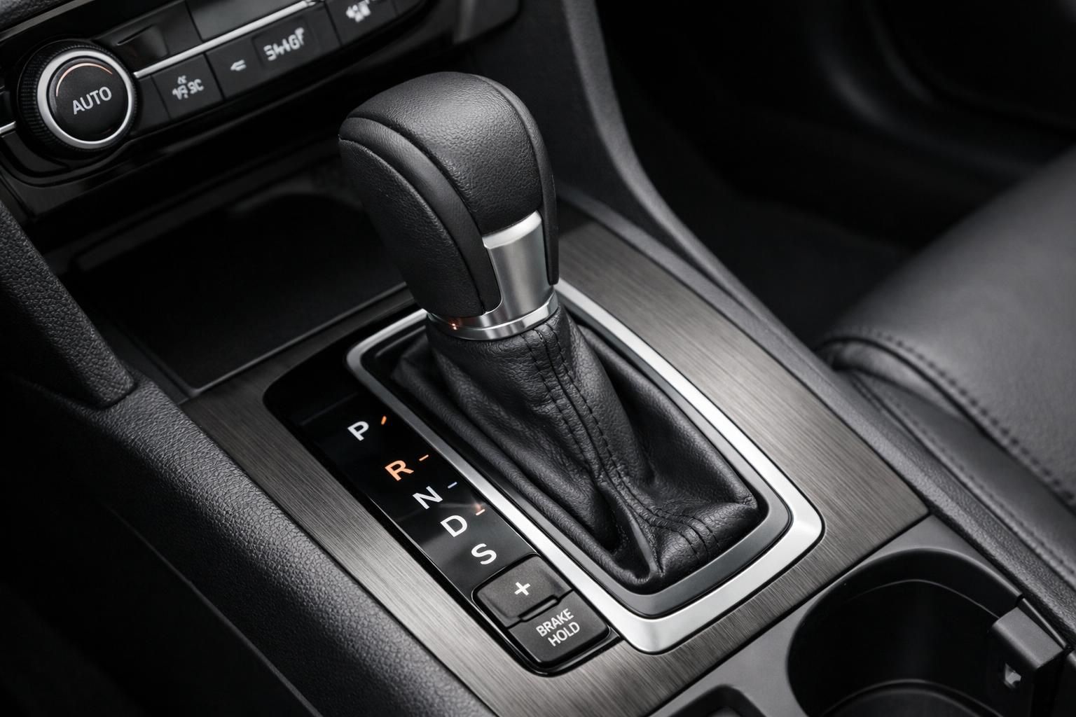 De middenconsole van de auto is voorzien van een automatische versnellingsbak, metallic accenten en bekerhouders.