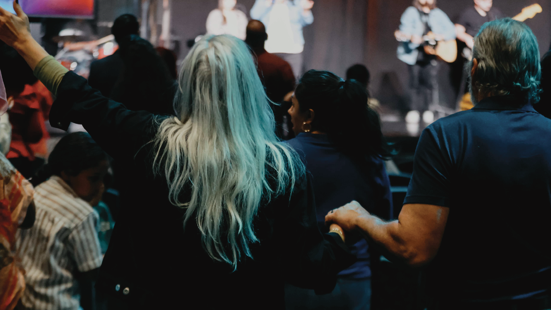 Crowd watching a live performance, with a person in the foreground raising an arm