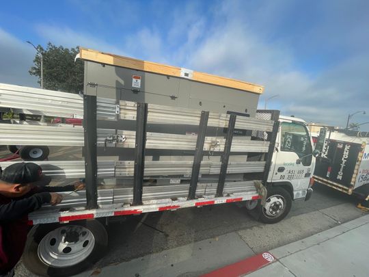 Truck loaded with long metal beams and a structure, a person is leaning against the side.