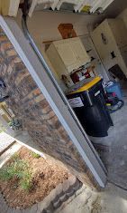 A garage door is open and a trash can is in the garage.