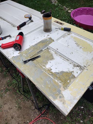 A white door is being repaired on a table with tools.
