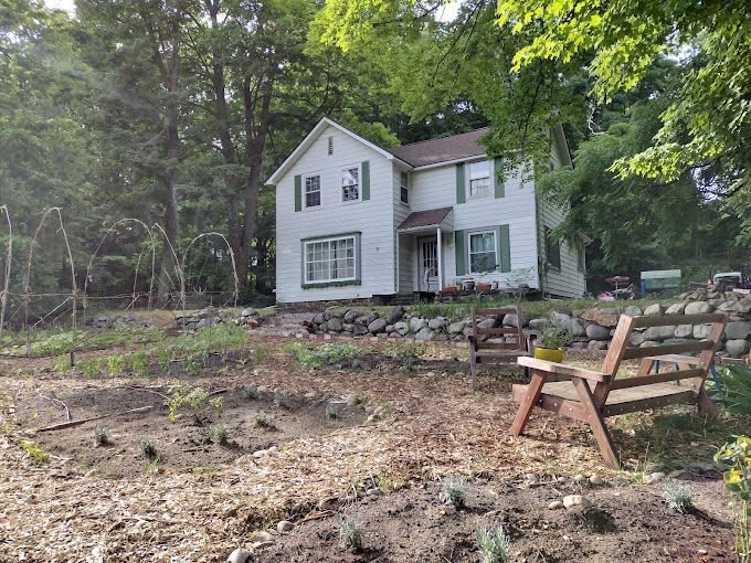 A white house with a wooden bench in front of it.