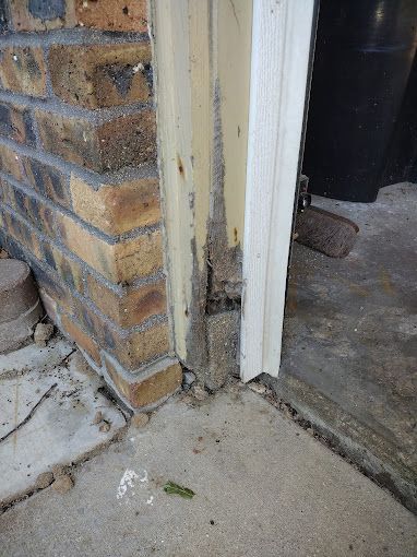 A brick wall with a door that has been damaged by termites.