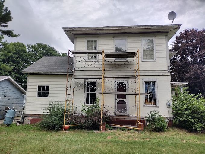 A white house with a scaffolding in front of it