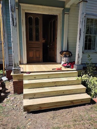 A set of wooden stairs leading up to the front door of a house.