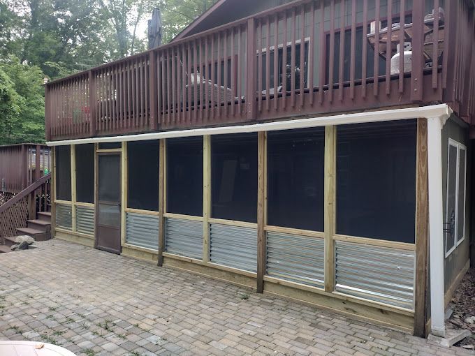 A screened in porch with a large deck on top of it.